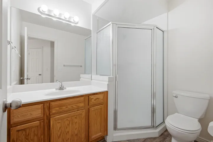Bathroom featuring a light wood-finish vanity with an integrated sink, a large wall mirror, and a contemporary vanity light fixture