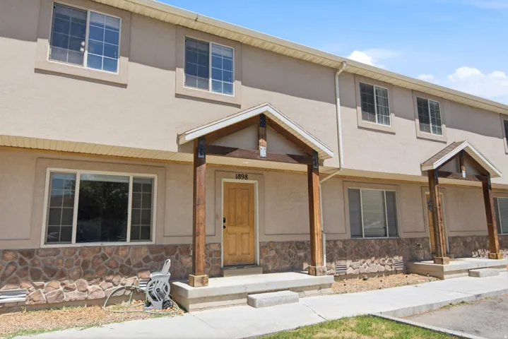 Two-story townhouse with stucco siding and a stone veneer foundation