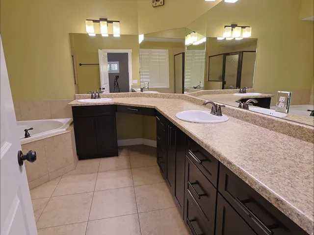 Dual vanity with dark wood-finish cabinetry, integrated sinks, and expansive countertop space