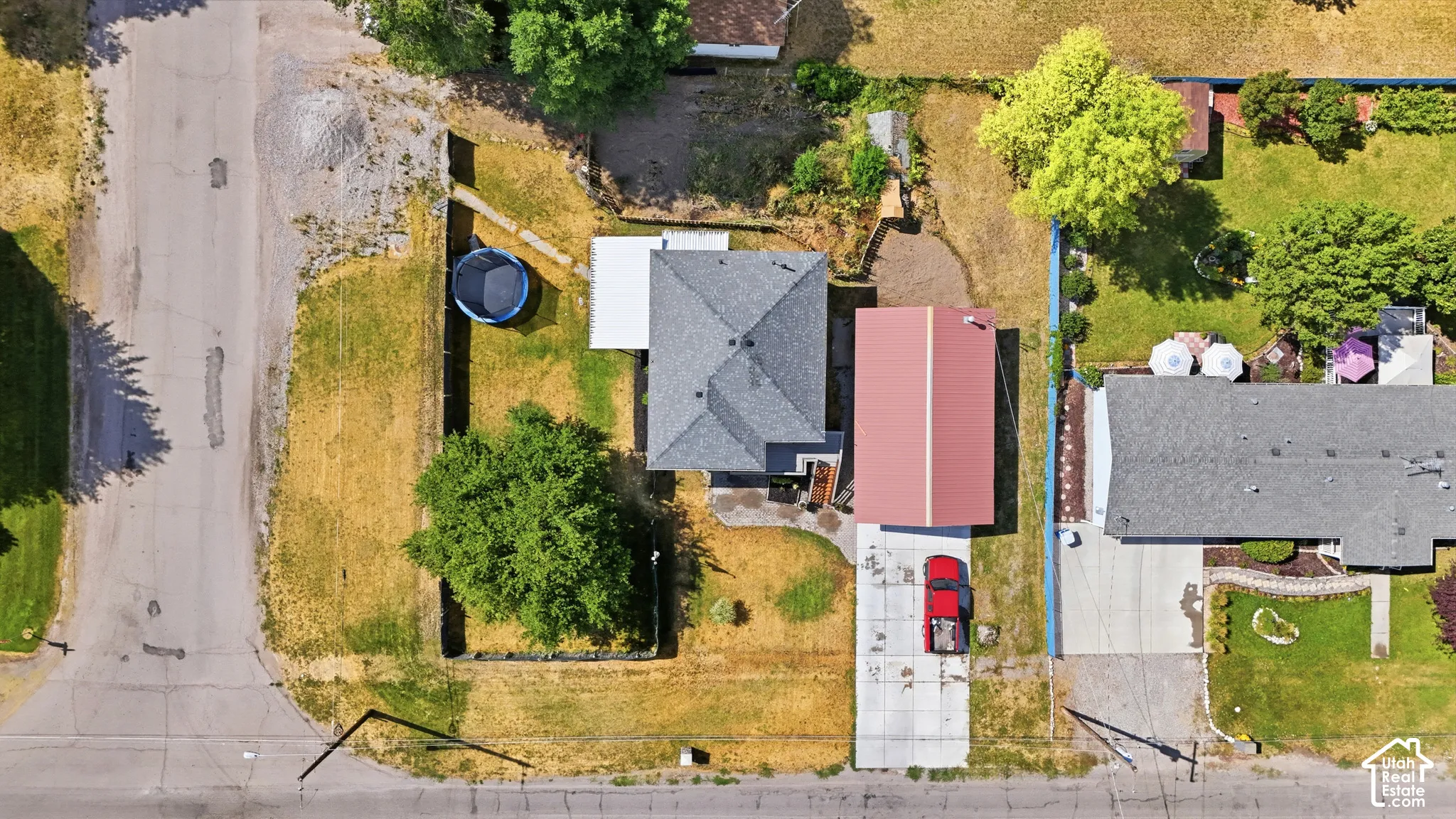 Aerial perspective showcasing a property with a grey shingle roof and an adjacent red metal-roofed structure