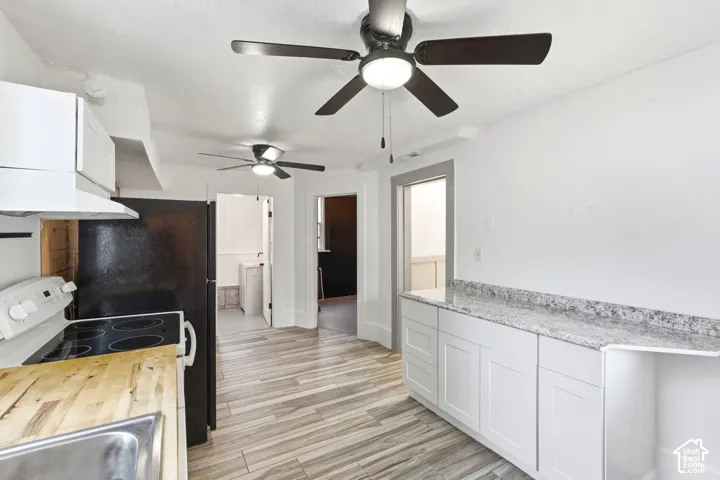 Kitchen featuring white cabinetry, gray speckled countertops, black appliances, wood-finish flooring, and two ceiling fans with integrated lighting