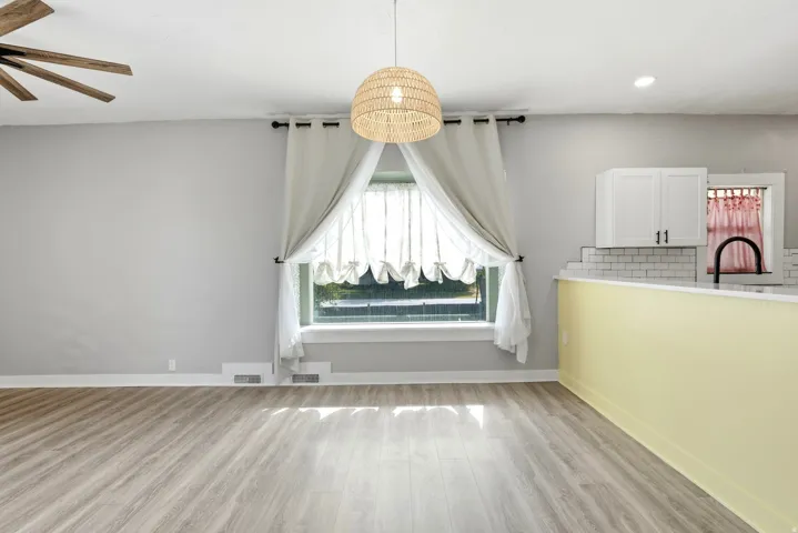 Spacious interior featuring wood-finish flooring, a large window with natural light, and a modern ceiling light fixture