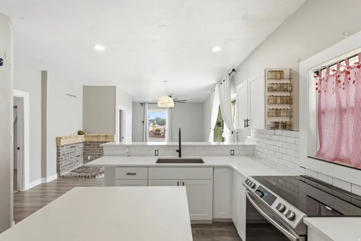Spacious kitchen featuring white cabinetry, light-toned countertops, and a white subway tile backsplash