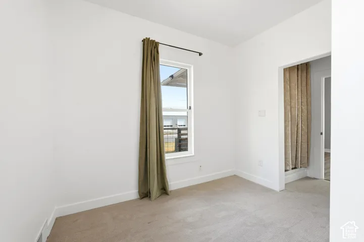 Carpeted room featuring a single window with a dark curtain rod and a light brown curtain