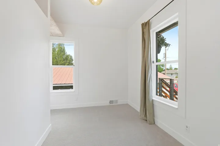 Room featuring two windows, light gray carpet, white walls, and a ceiling-mounted light fixture