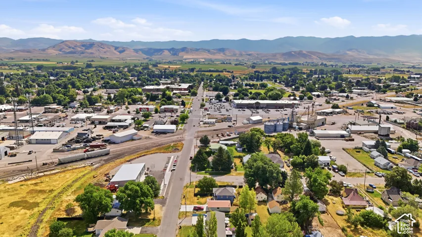 Aerial perspective showcasing a mixed-use commercial and residential district with surrounding green fields and distant mountains