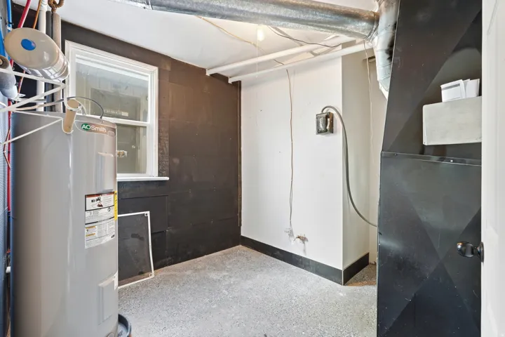 Utility area featuring a water heater, visible ductwork, and a single window