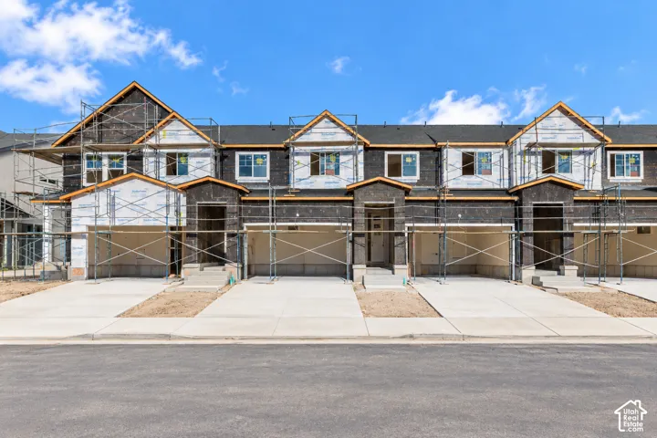 Newly constructed townhomes featuring multiple gabled rooflines, individual driveways, and integrated garages