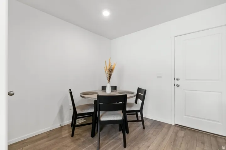 Bright dining area featuring wood-finish flooring, recessed lighting, and a paneled door
