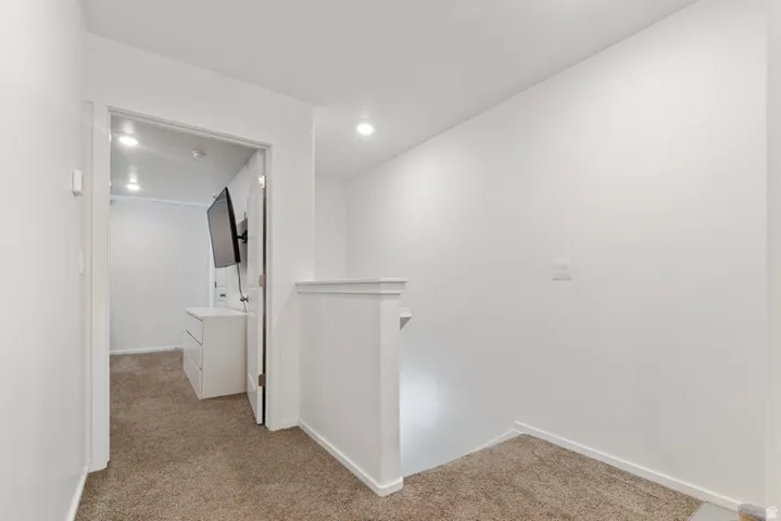 Hallway featuring neutral-toned carpeting, white painted walls, and recessed lighting