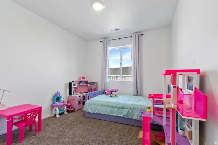 Carpeted room featuring a large window with vertical blinds, white walls, and a ceiling light fixture