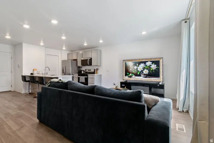 Open-concept living space featuring wood-finish flooring, recessed lighting, and white walls