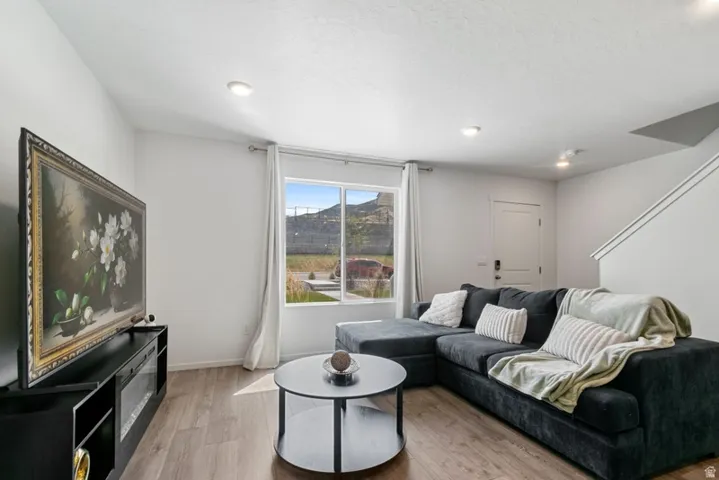 Living area featuring wood-finish flooring, recessed lighting, and a large window with a mountain backdrop