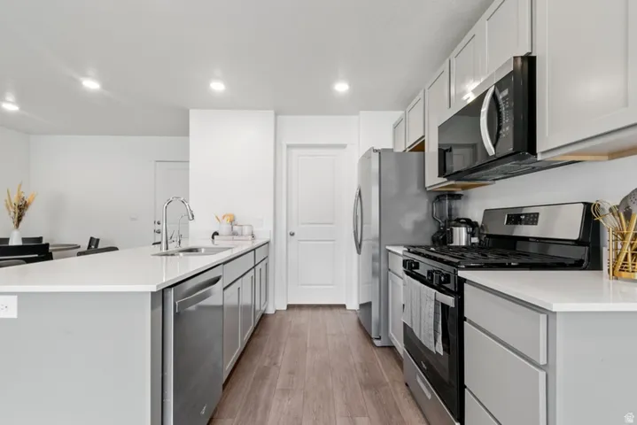 Modern kitchen featuring wood-finish flooring, recessed lighting, and light grey cabinetry