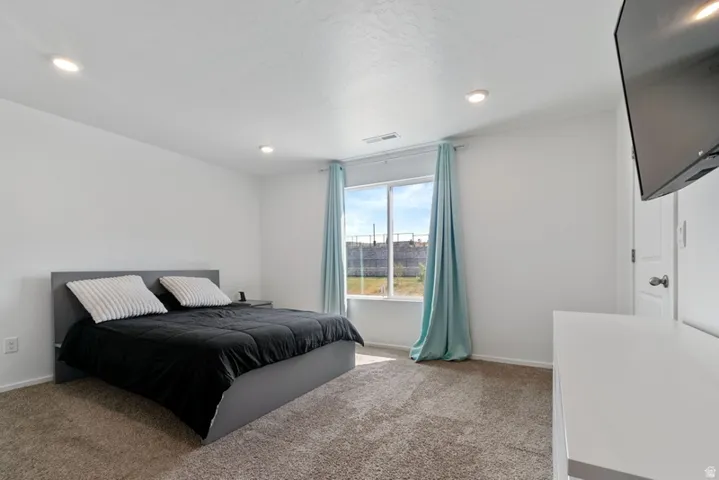 Bedroom featuring a carpeted floor, recessed lighting, and a large window