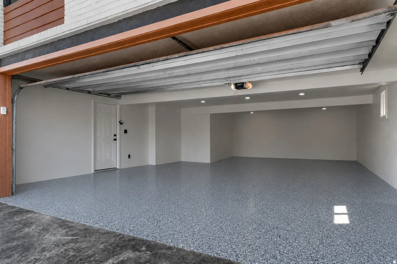 Spacious garage featuring a speckled epoxy floor, recessed lighting, and a white paneled door