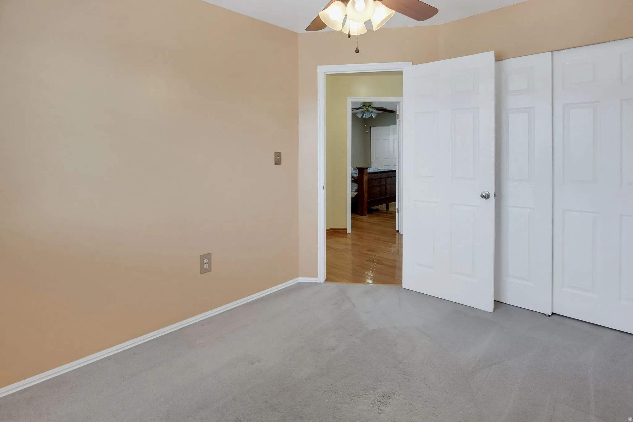 Carpeted room with a ceiling fan light fixture and neutral-toned walls