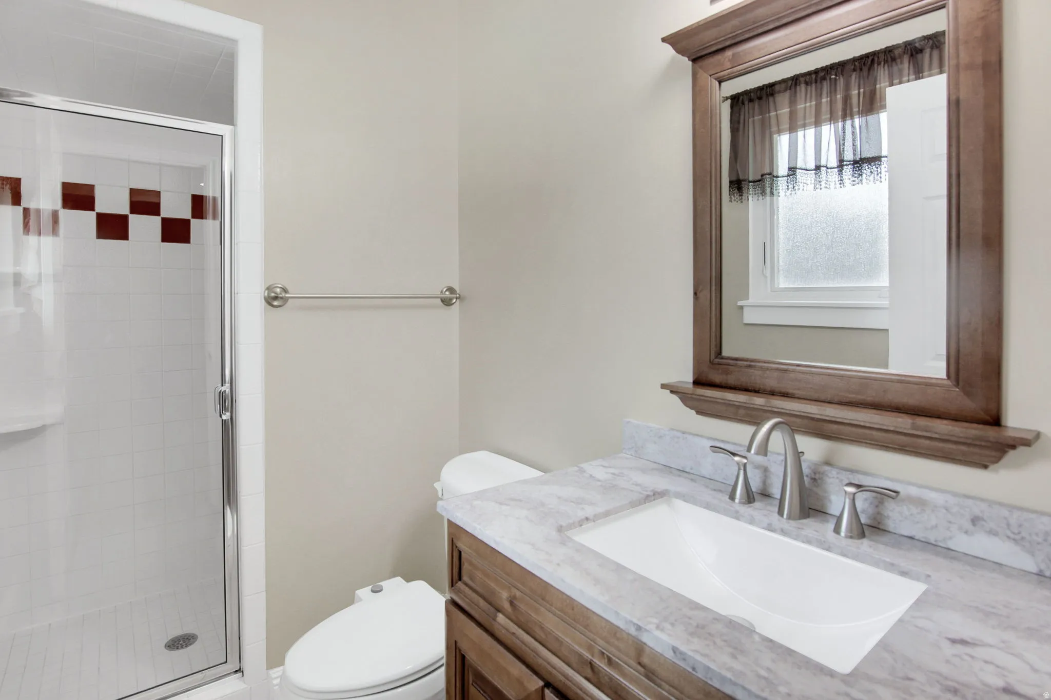 Contemporary vanity with a rectangular undermount sink, stone countertop, and brushed nickel faucet