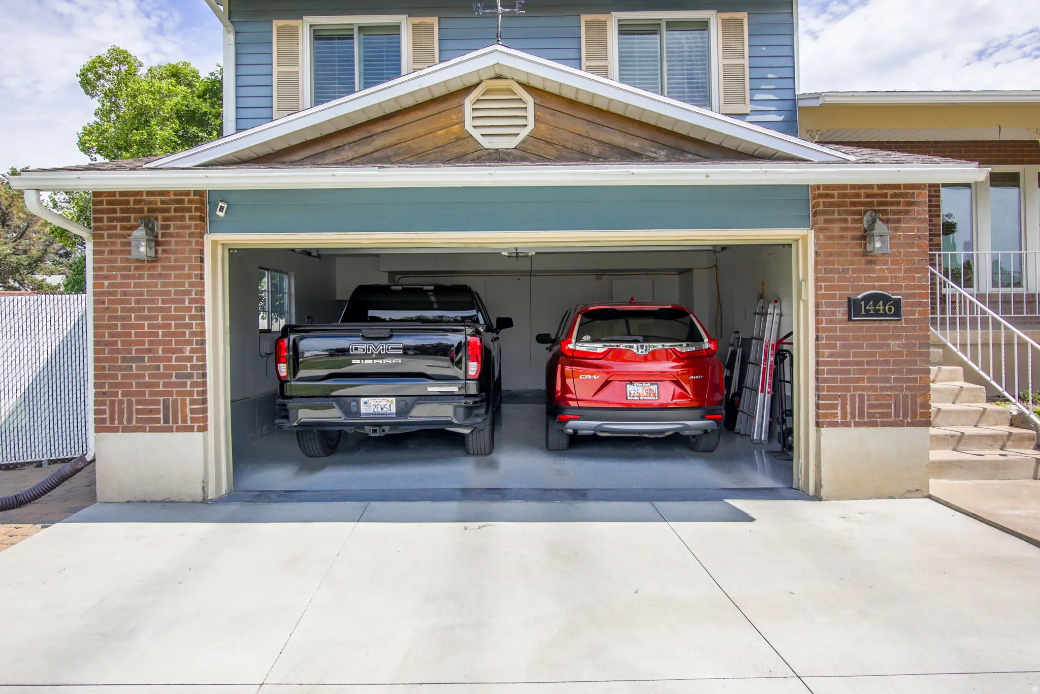 Two-car garage with brick facade accents, overhead lighting, and concrete driveway