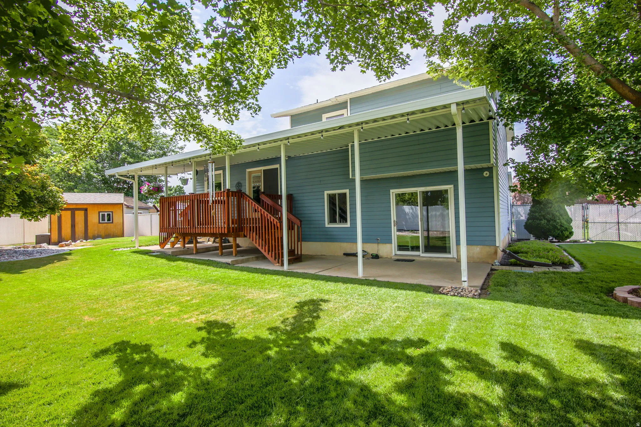 Expansive backyard featuring a large green lawn, covered patio, and a multi-level wood deck with stairs