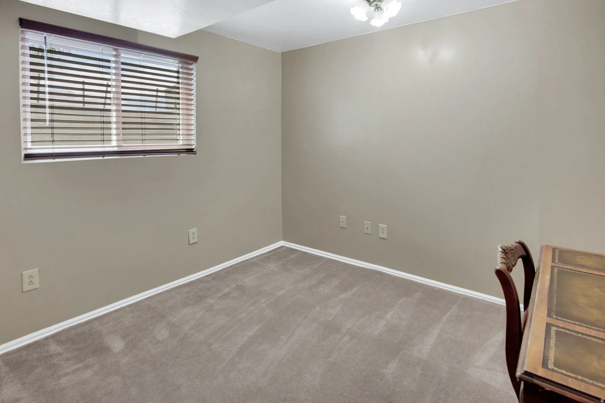 Carpeted room featuring a window with horizontal blinds, neutral wall paint, and white baseboards