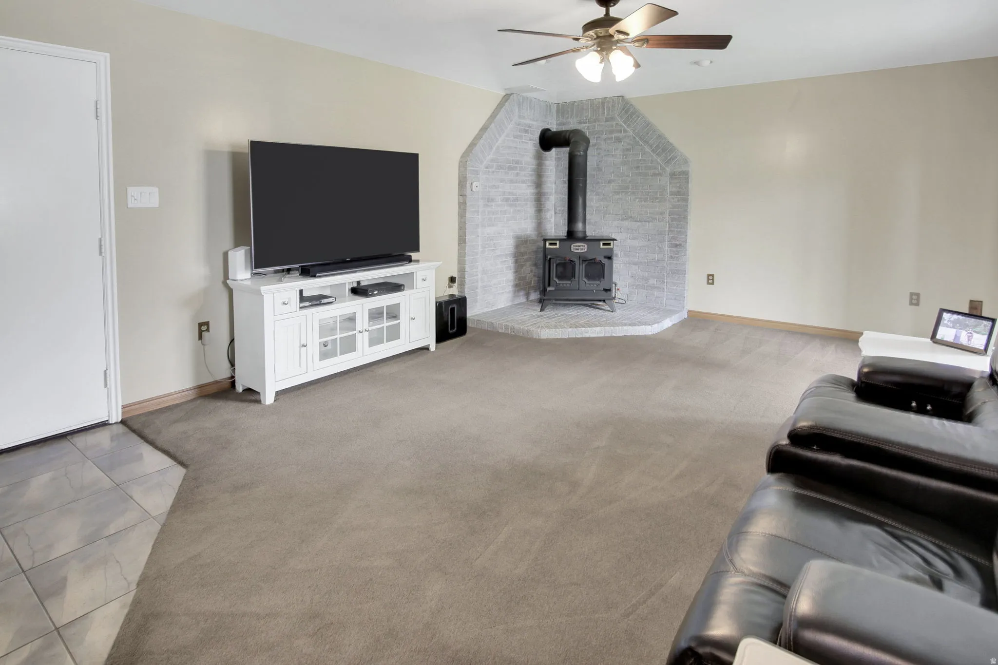 Spacious living area featuring a corner wood-burning stove with a brick surround