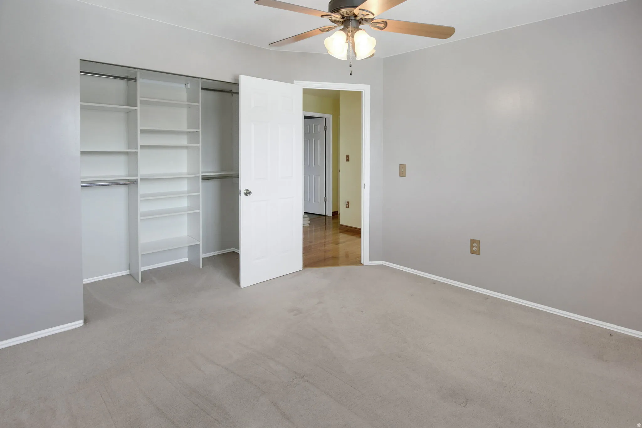 Bedroom featuring carpet flooring, a ceiling fan with light fixture, and a built-in closet system with shelving and hanging rods