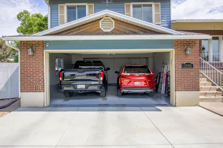 Two-car garage with brick facade accents, overhead lighting, and concrete driveway