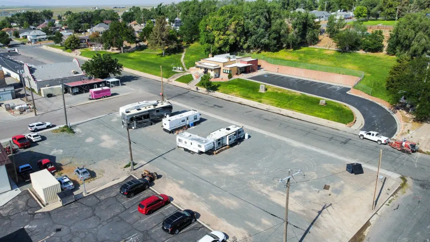 Expansive commercial property featuring a large paved lot, multiple structures, and additional unpaved parking areas
