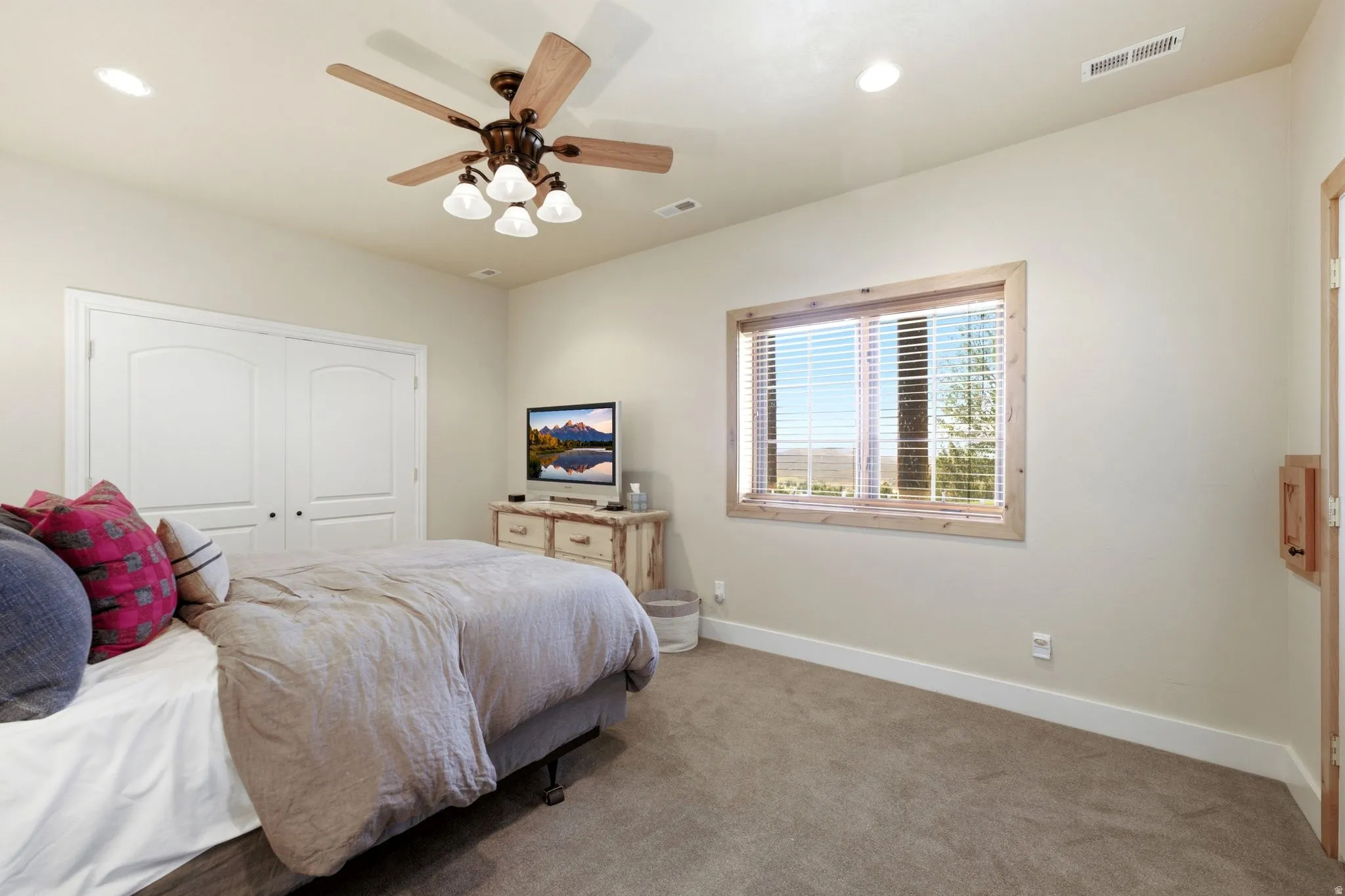 Recessed lighting, ceiling fan with light kit, and a broad window with wood trim