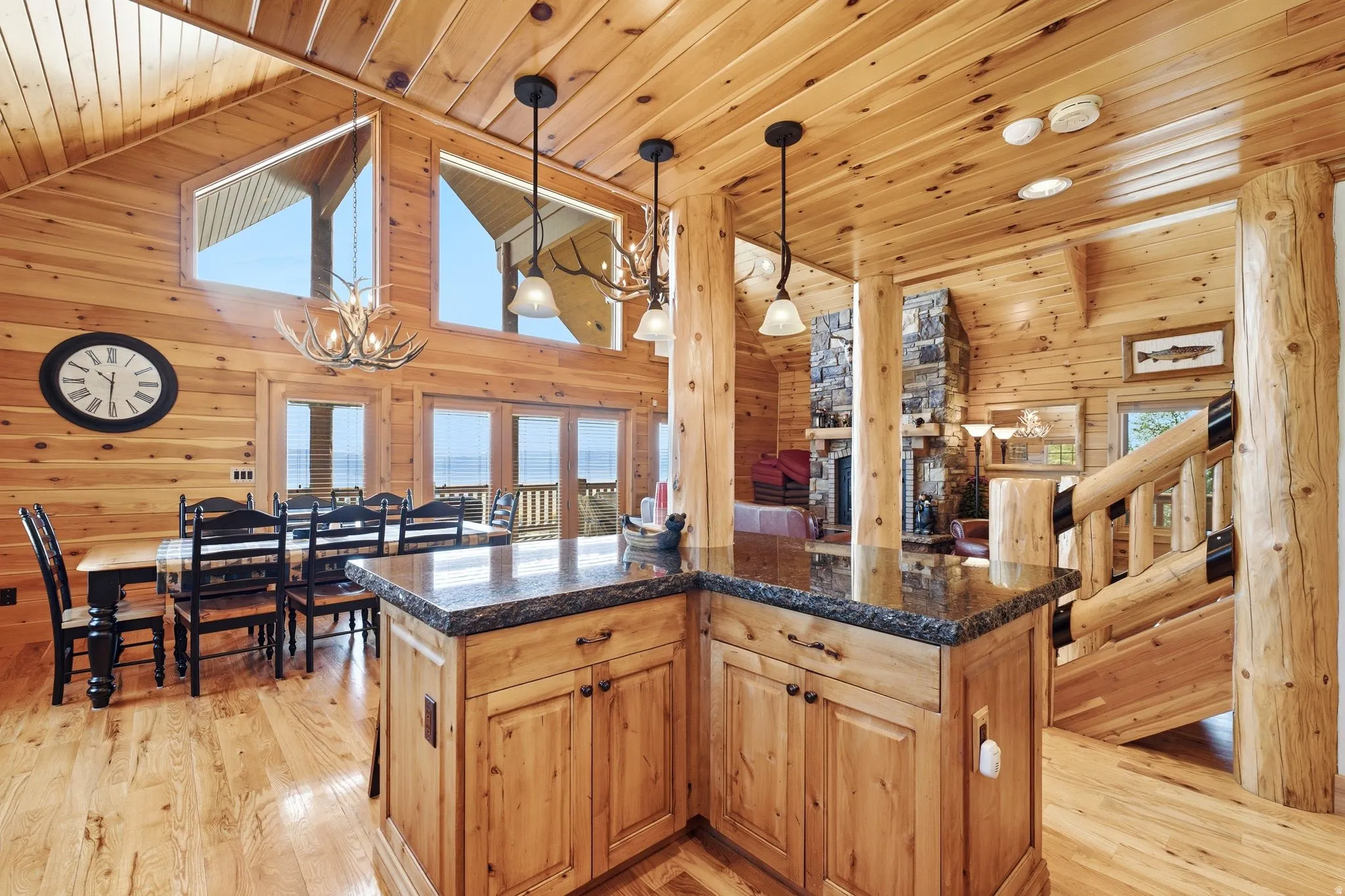 Open-concept living space with extensive wood paneling and log beam accents