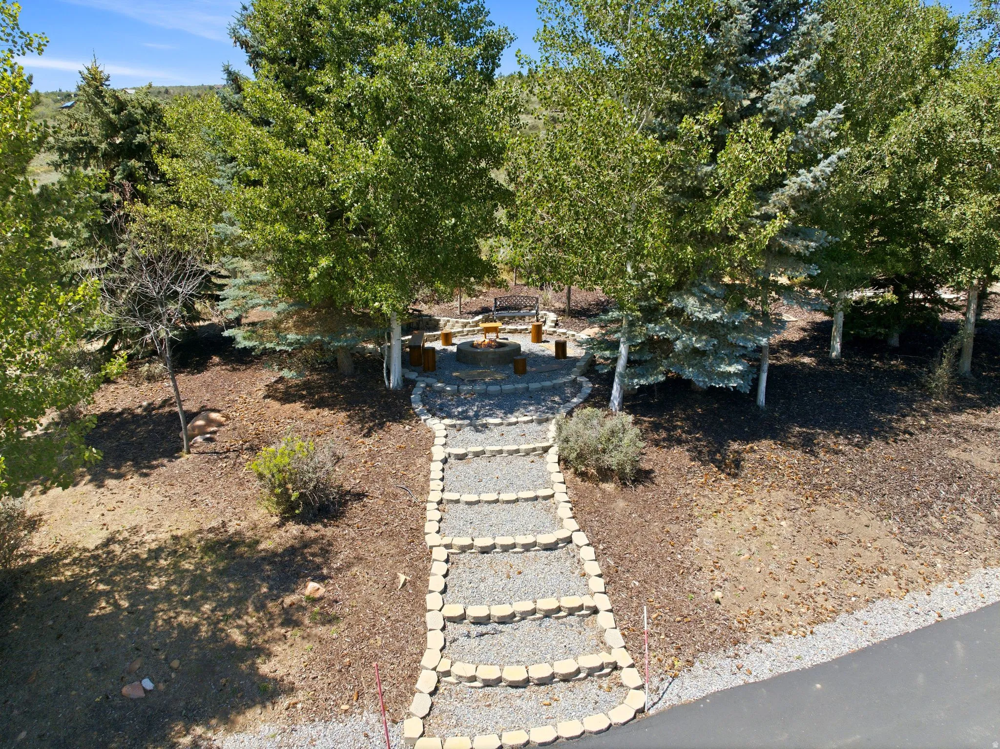 Landscaped pathway constructed with stone risers and gravel leading to a circular stone patio