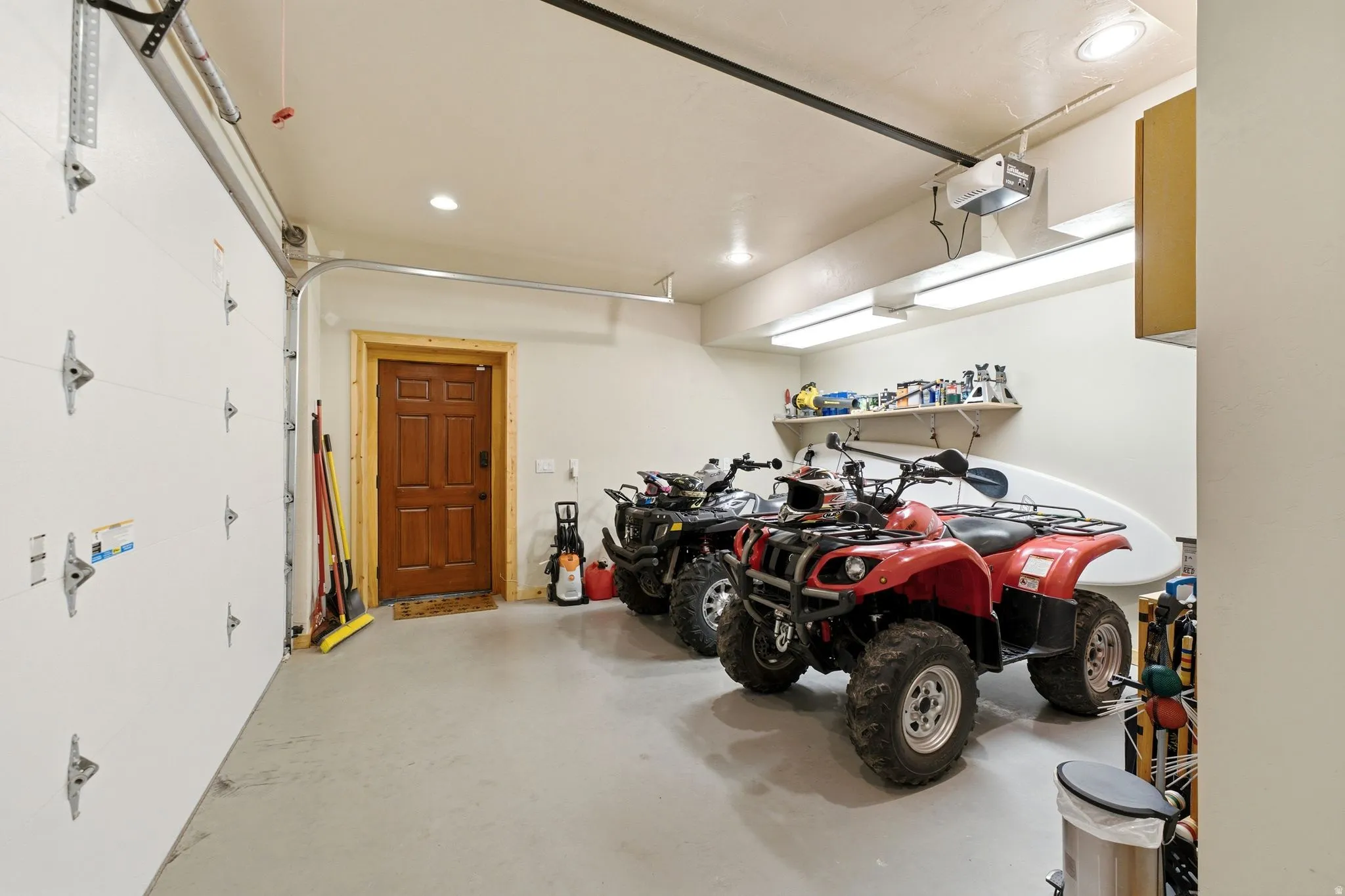 Concrete flooring garage with an insulated garage door, recessed lighting, and a wood-panel interior door