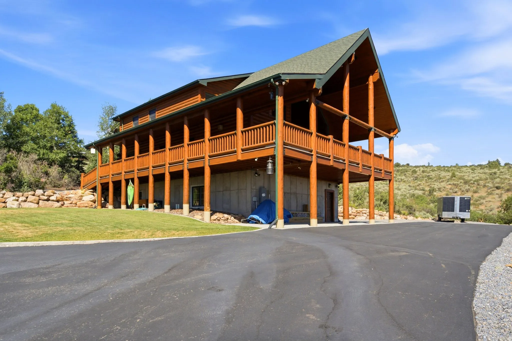 Log-style architecture featuring a prominent gable roofline and expansive wrap-around deck