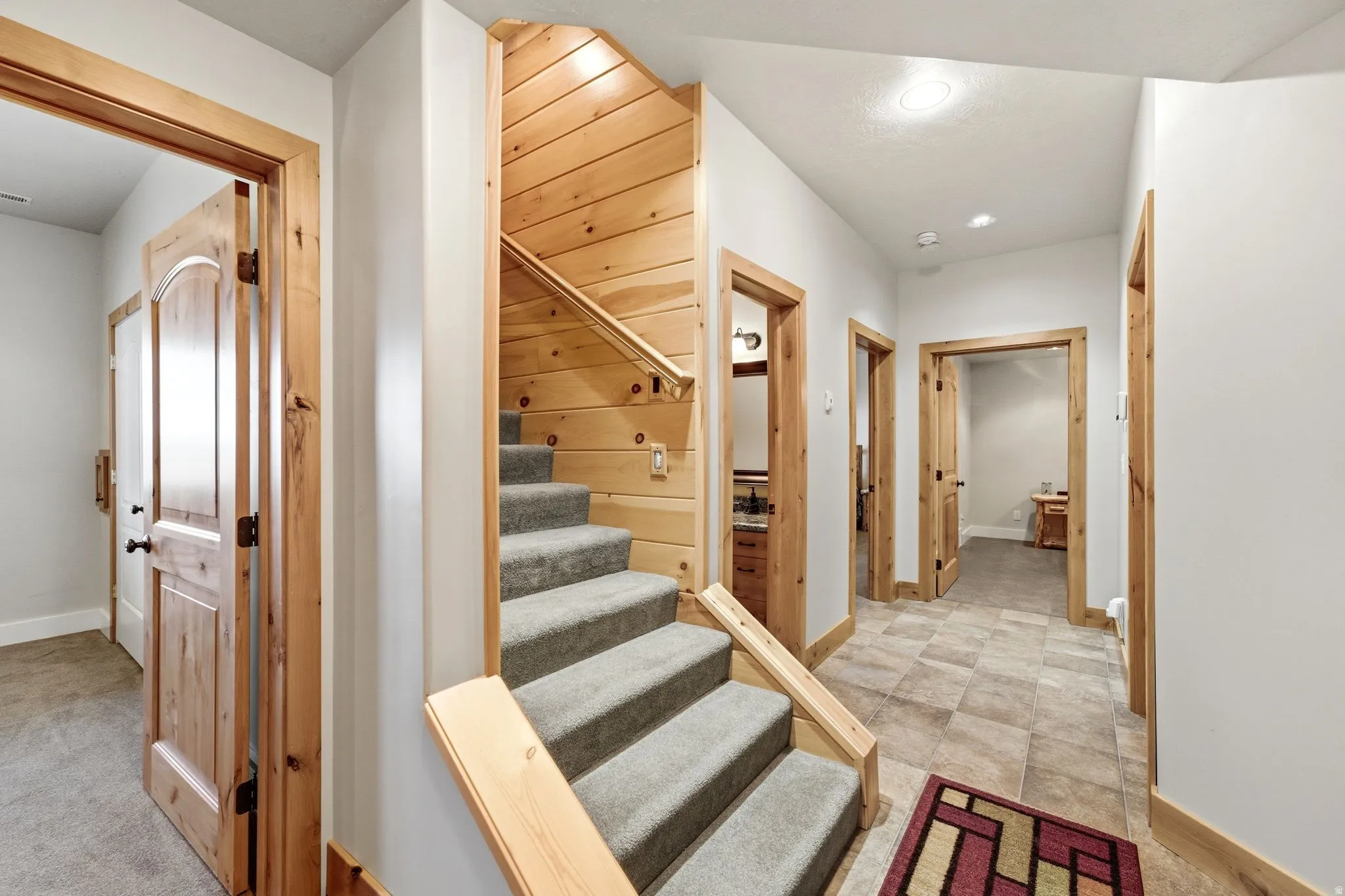 Carpeted staircase with wood-paneled walls and a matching wood handrail