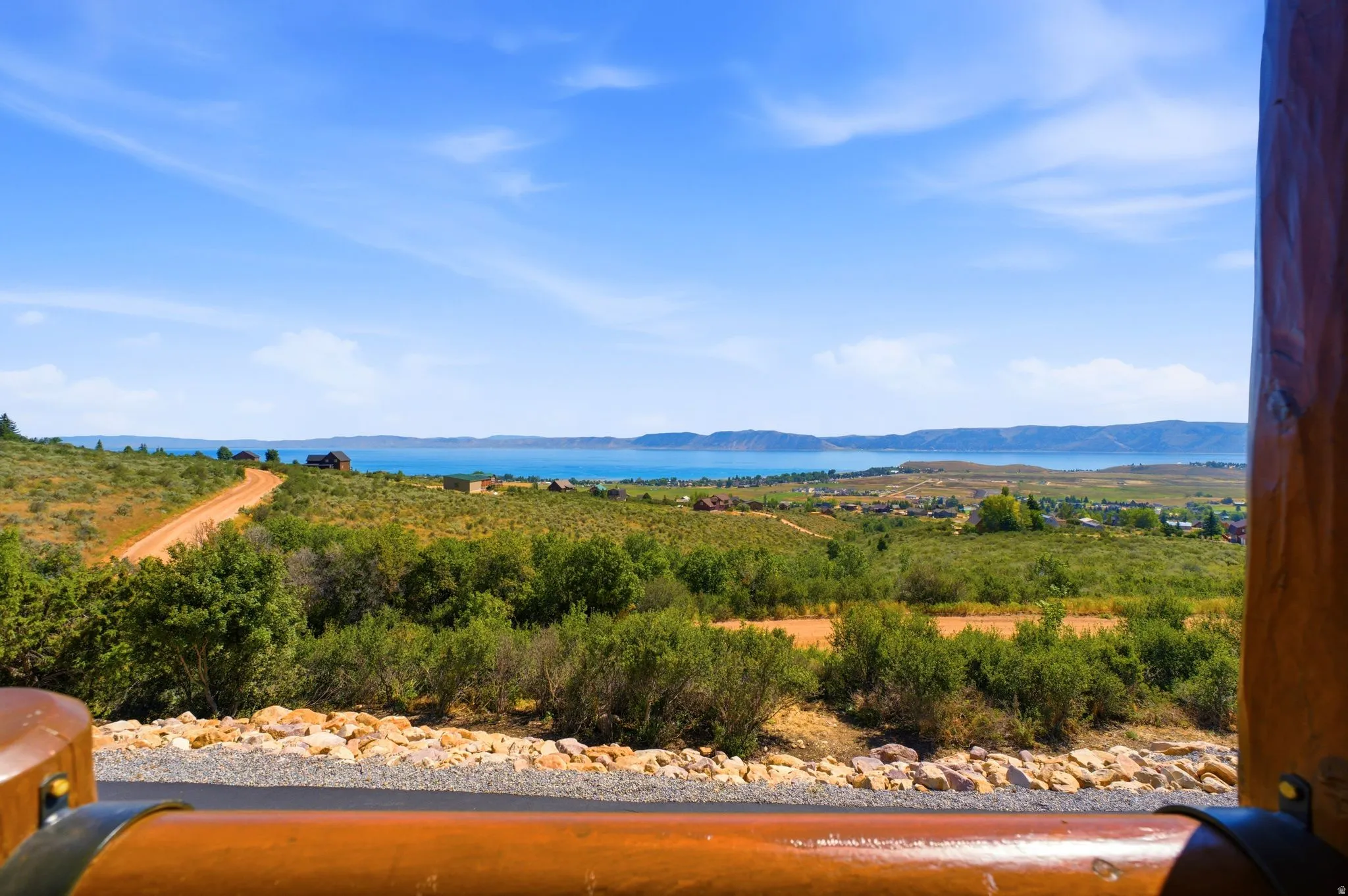 Expansive landscape featuring a large body of water, distant hills, and varied terrain under a clear sky