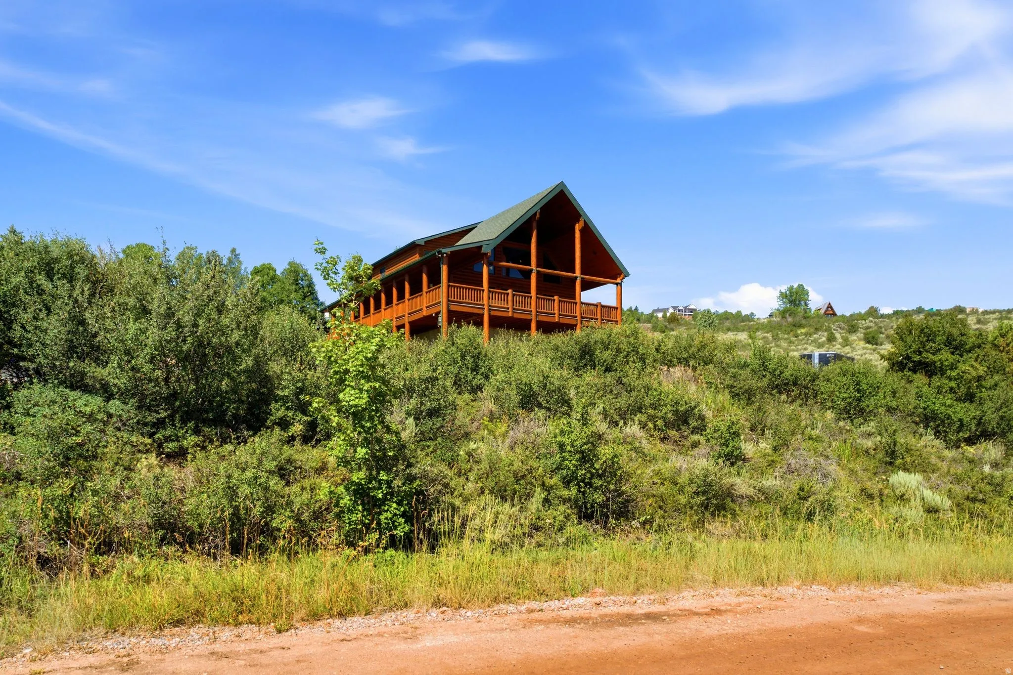 Rustic-style log home with a multi-level deck, dark-pitched roofline, and exposed timber framing