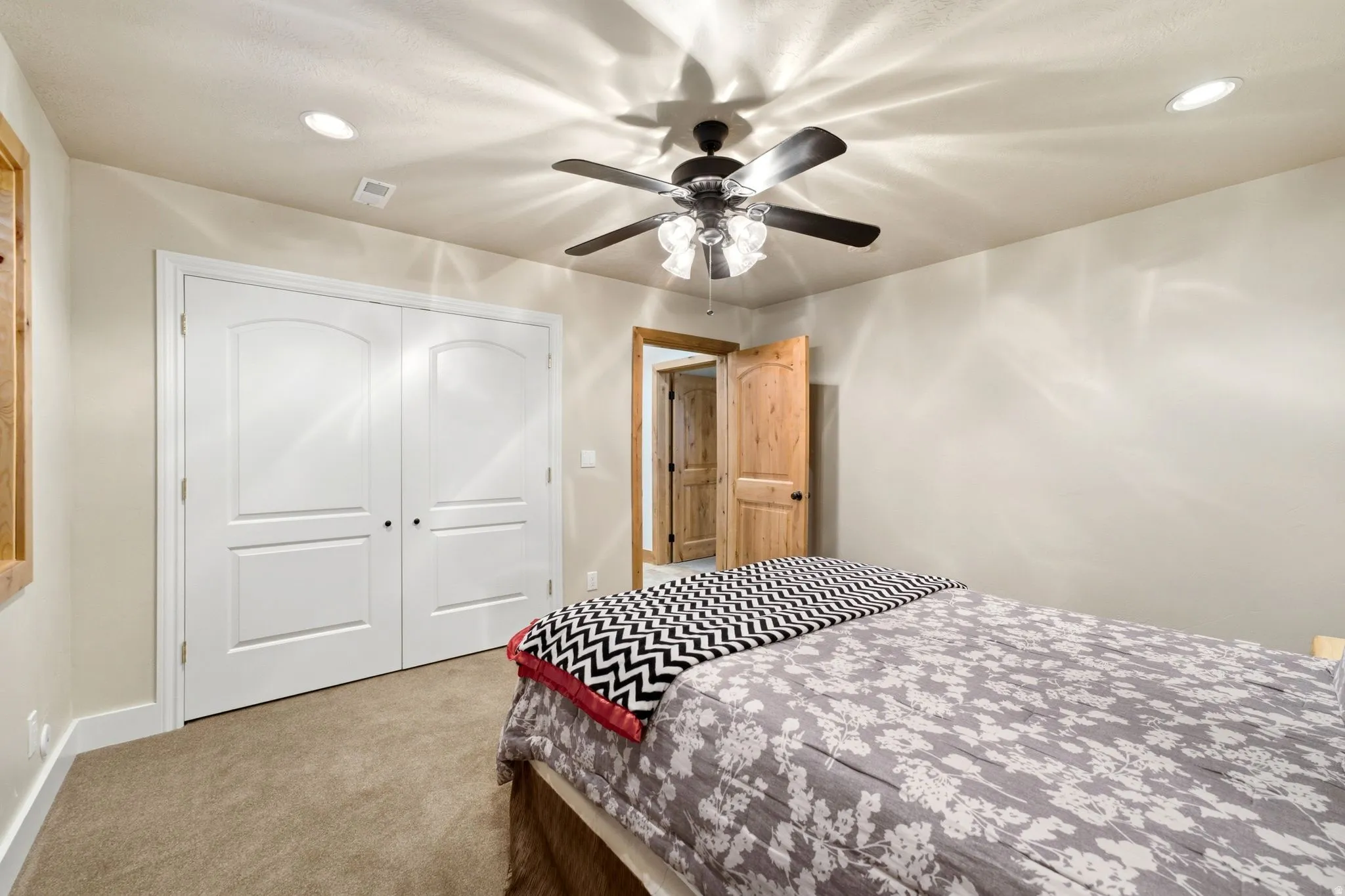 Bedroom featuring carpet flooring, a ceiling fan with integrated lighting, recessed lighting, white bifold closet doors, and wood-paneled interior doors