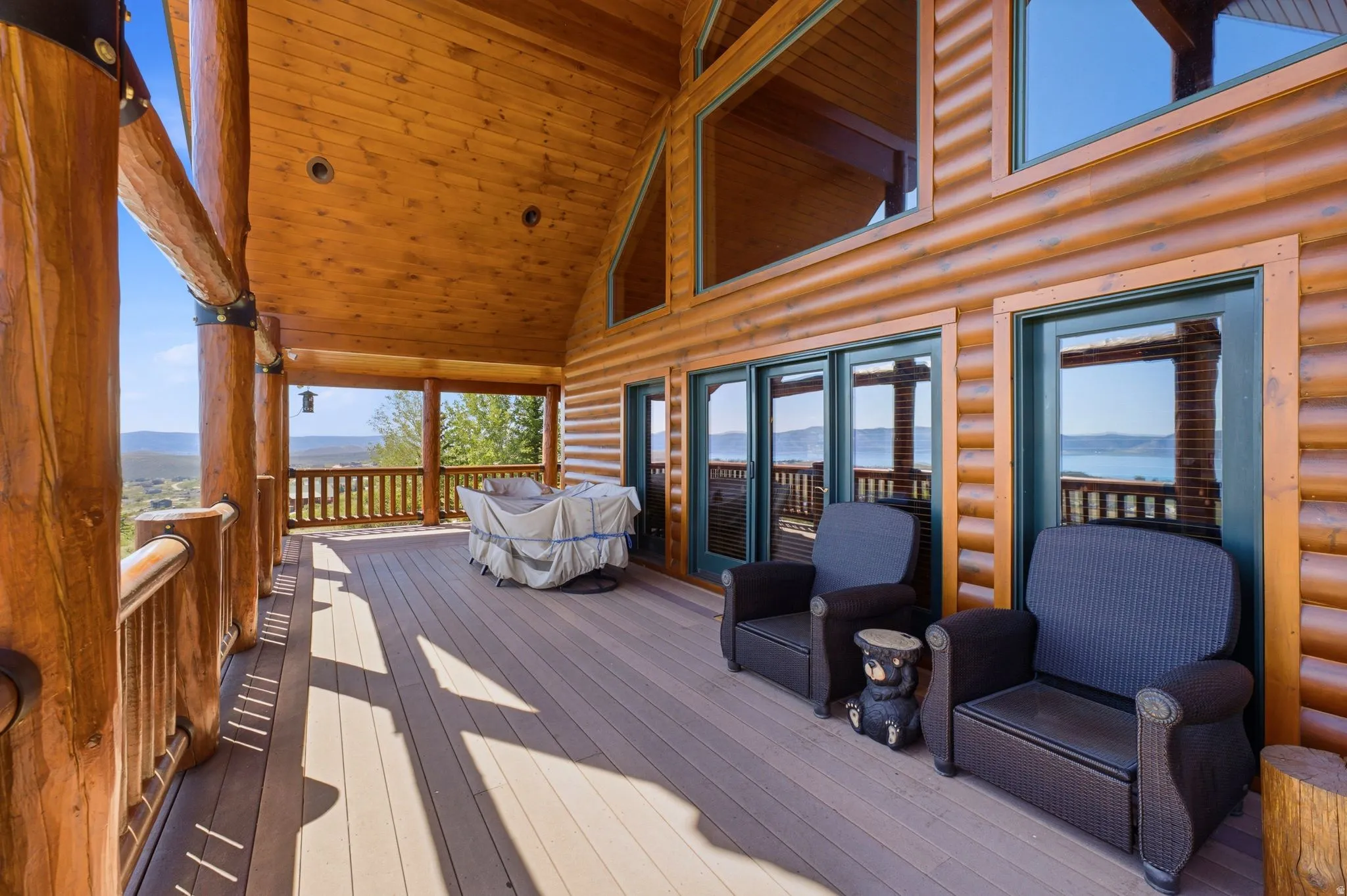 Expansive log cabin-style deck featuring a composite wood-finish floor and exposed wooden beams