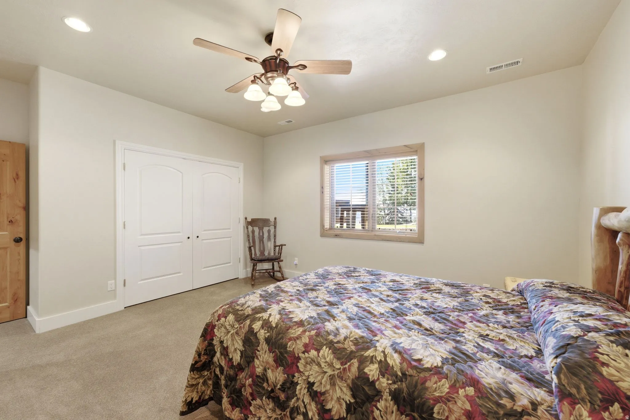 Neutral-toned room featuring a window with natural wood trim, recessed lighting, and a ceiling fan