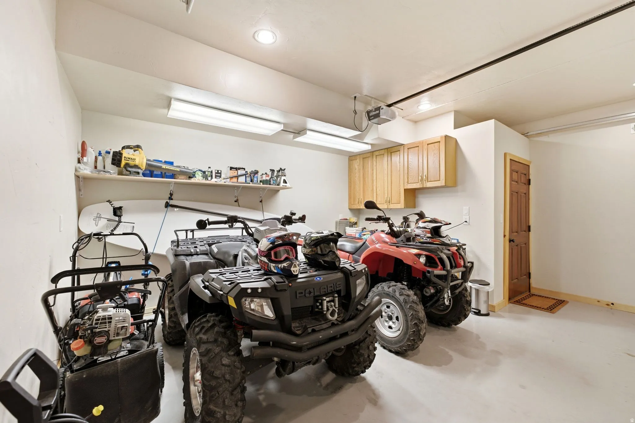Spacious garage featuring light-toned walls, wood-finish cabinetry, built-in shelving, recessed lighting, and a durable finished floor