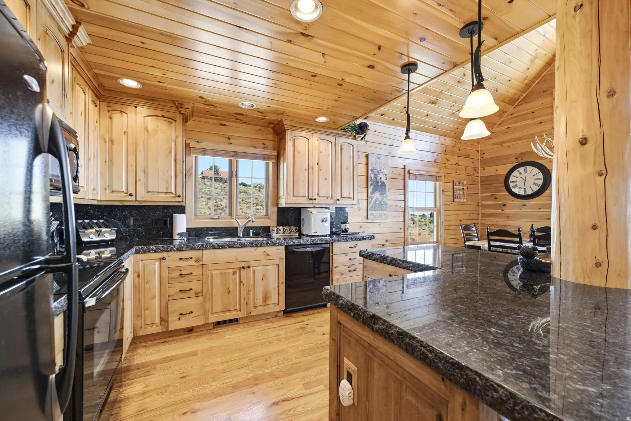Kitchen featuring natural wood cabinetry, wood-finish flooring, and black appliances