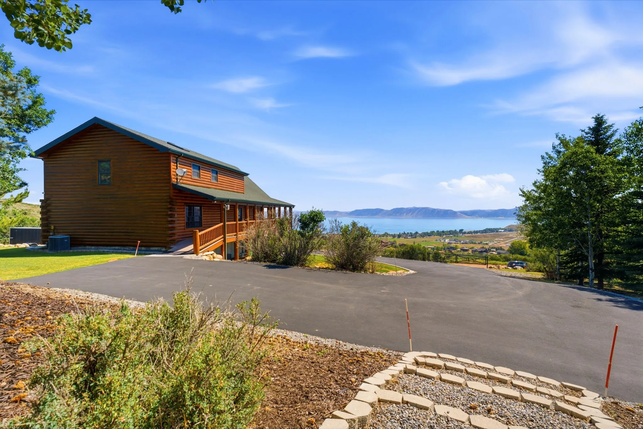 Wood-sided home featuring a wrap-around porch and an expansive paved driveway