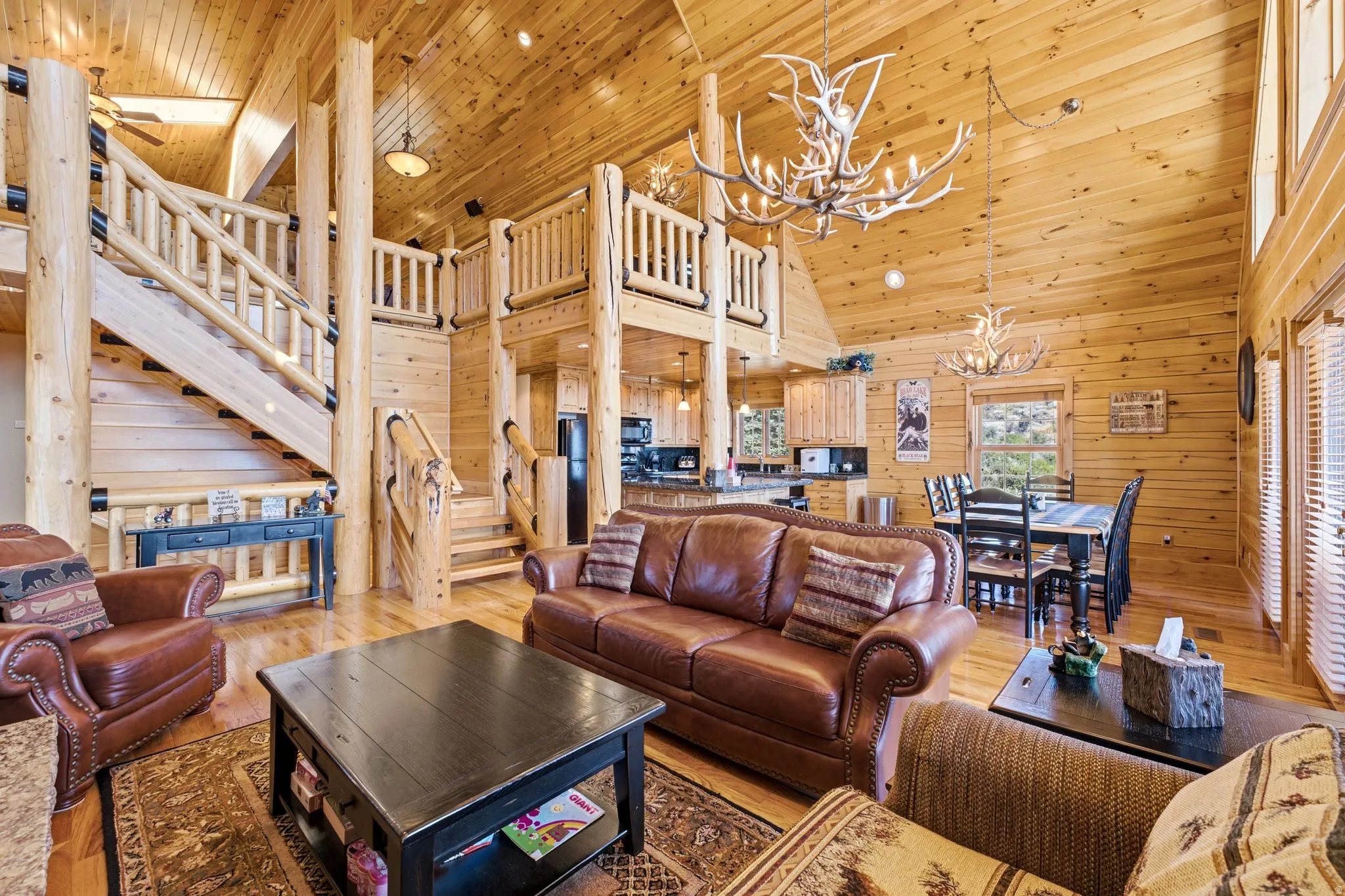 Expansive great room featuring vaulted ceilings with wood paneling, exposed log beams, and wood-finish flooring