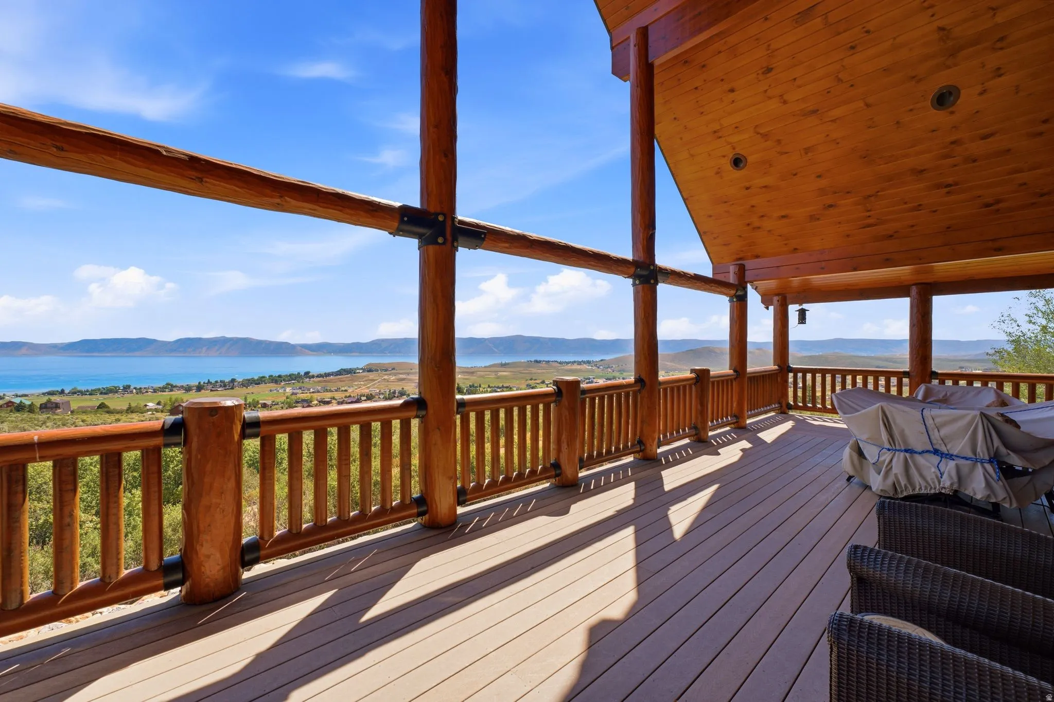Expansive covered deck featuring wood-finish railings and posts, a composite deck surface, and a tongue-and-groove wood ceiling with recessed lighting
