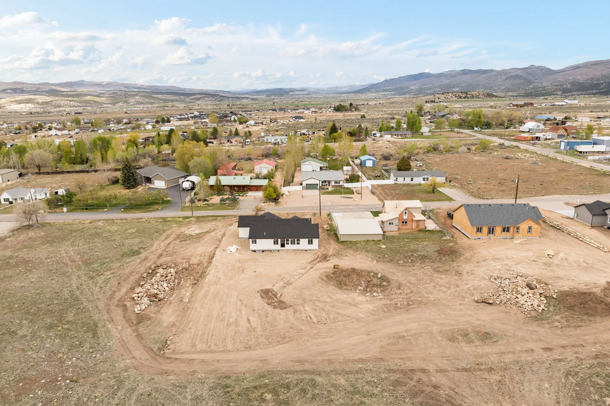 Newly constructed residence featuring a white exterior, dark roof, and a surrounding undeveloped lot
