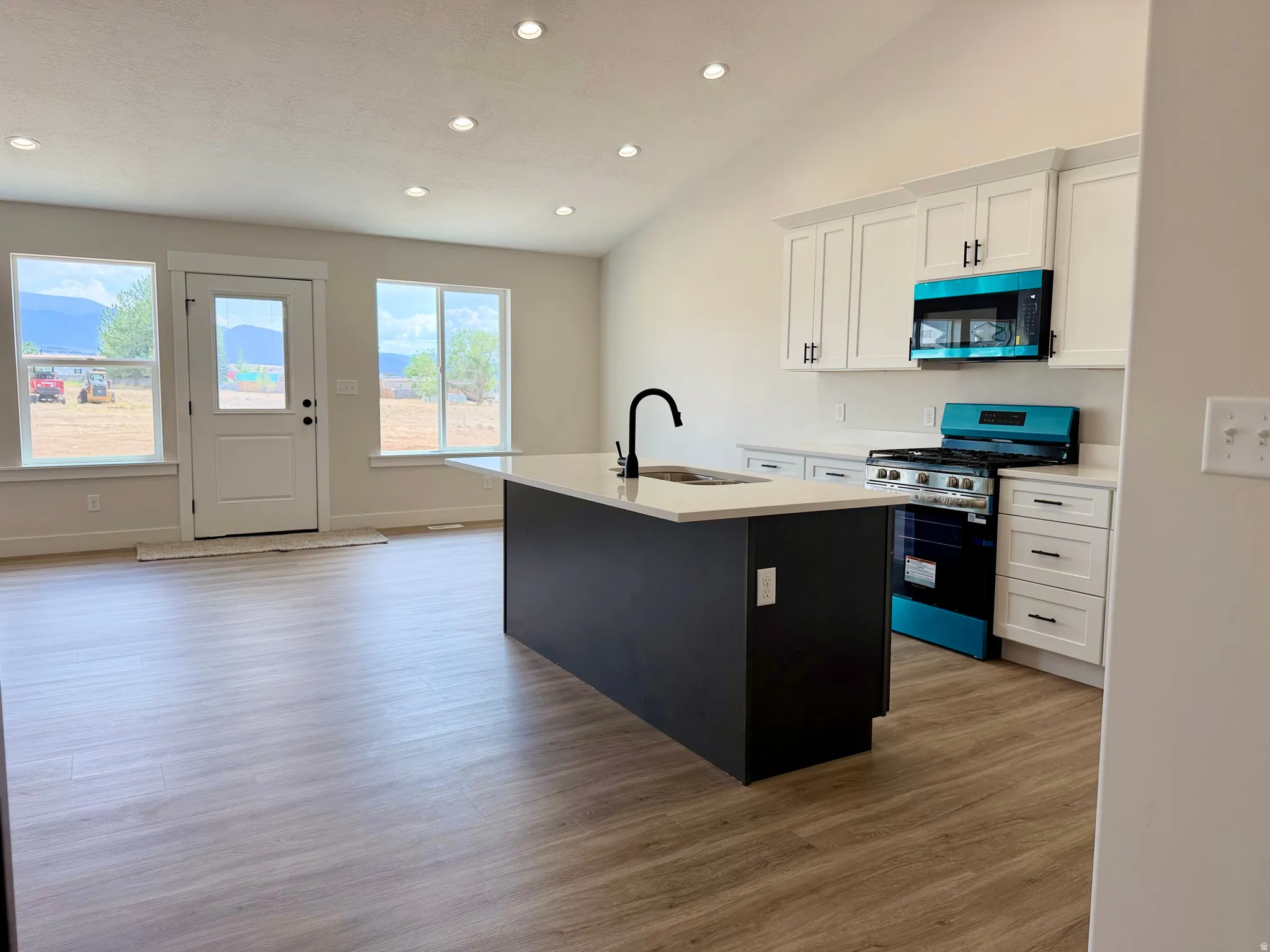 Kitchen with two-tone custom cabinetry with soft-close. Center island sink and dishwasher and stainless steel appliances