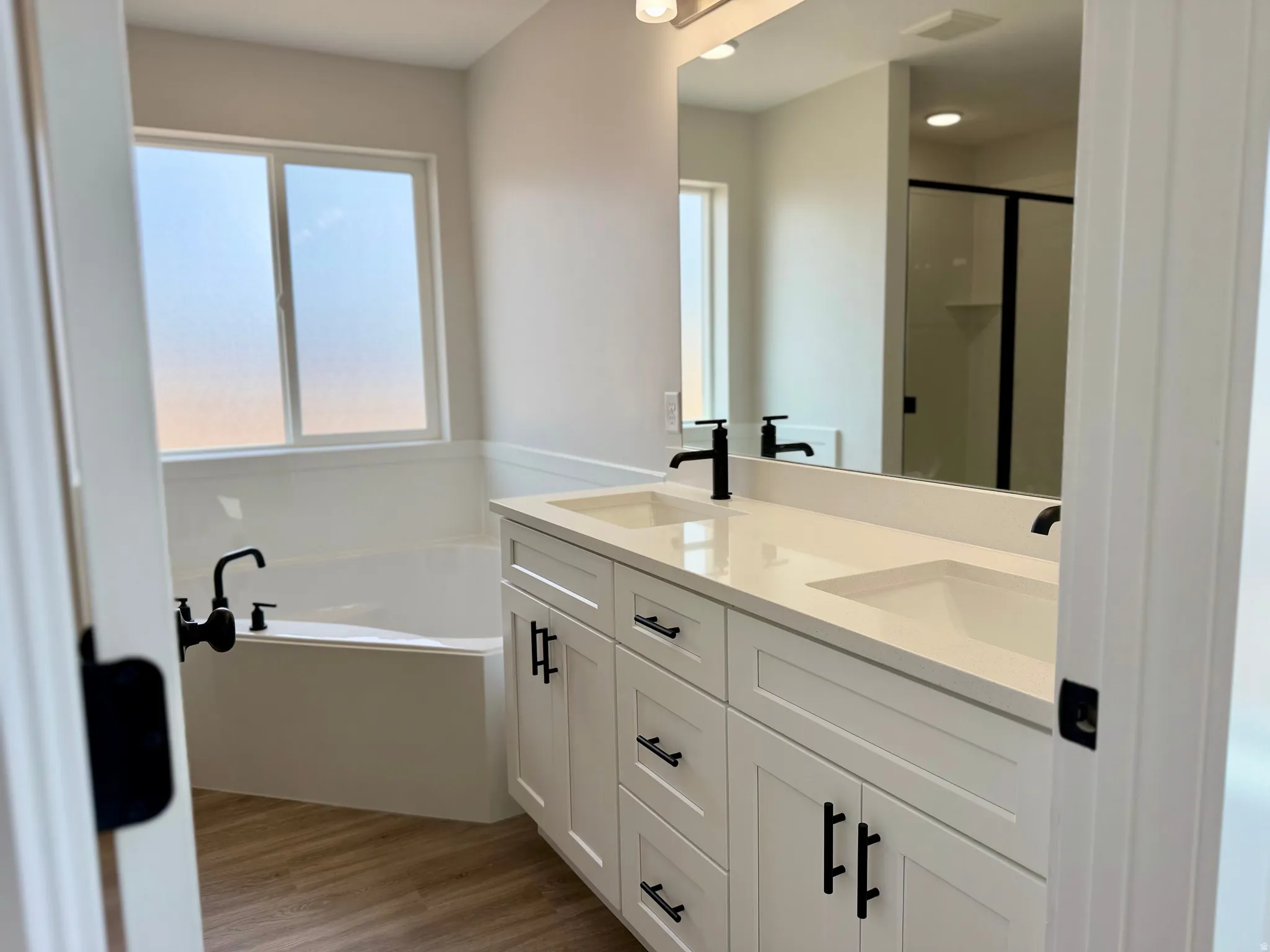 Primary ensuite bathroom with dual vanities, oversized corner tub and separate shower