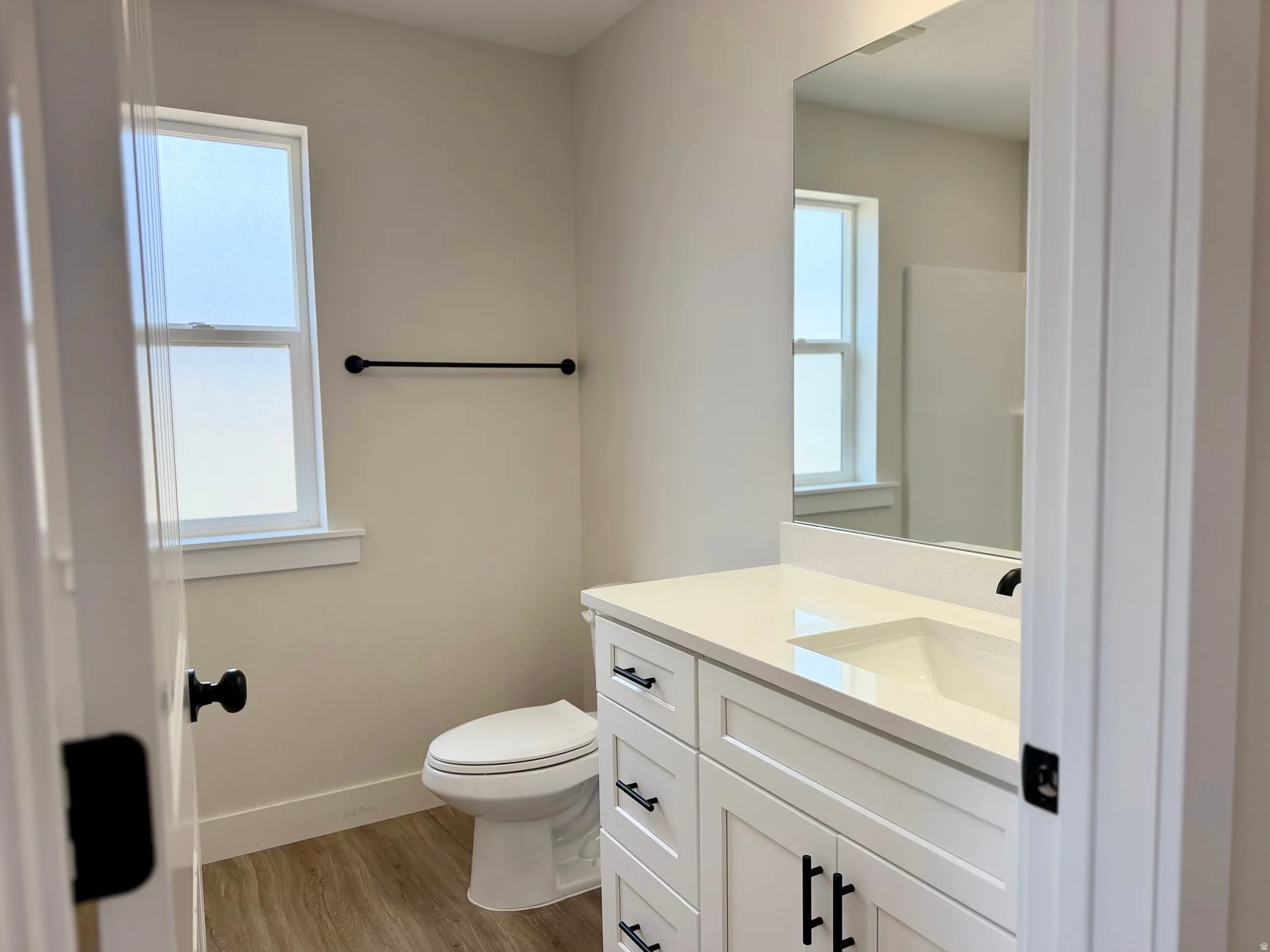Bathroom featuring a white vanity with an integrated sink, quartz countertop, and matte black hardware