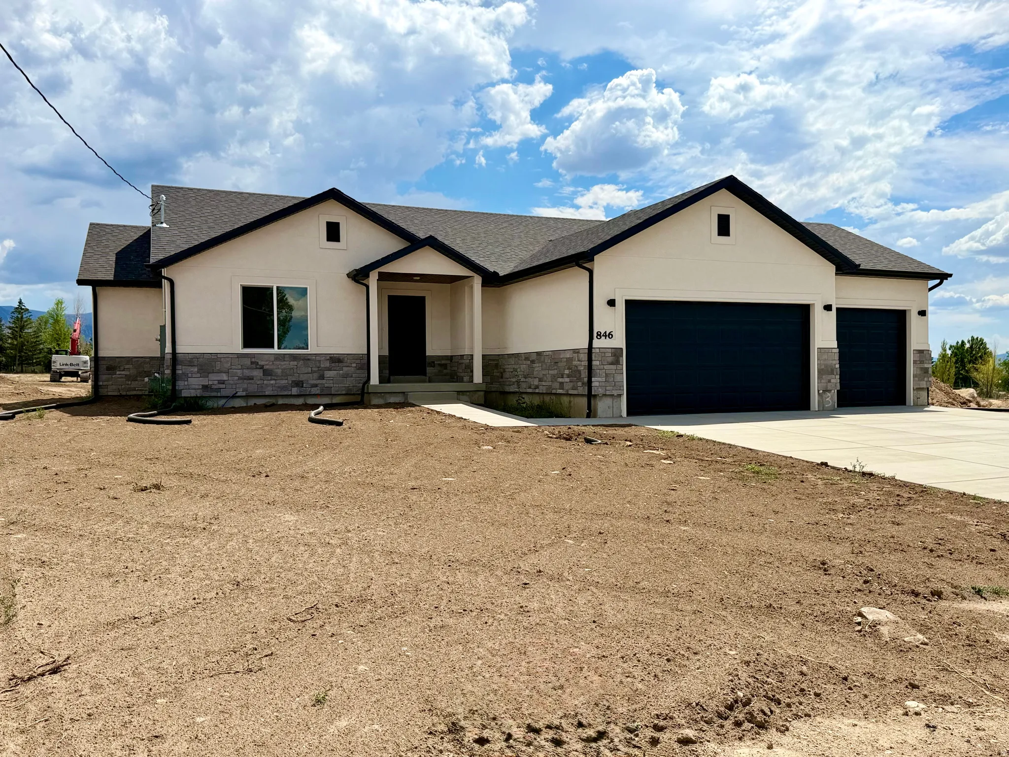 New ranch-style home featuring a cream stucco facade and dark gray stone accents